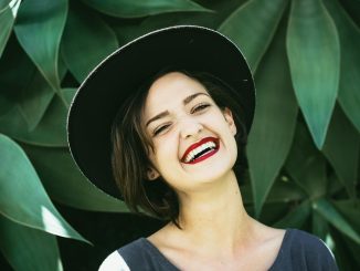 Woman Smiling In Front Of Green Plants