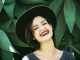 Woman Smiling In Front Of Green Plants